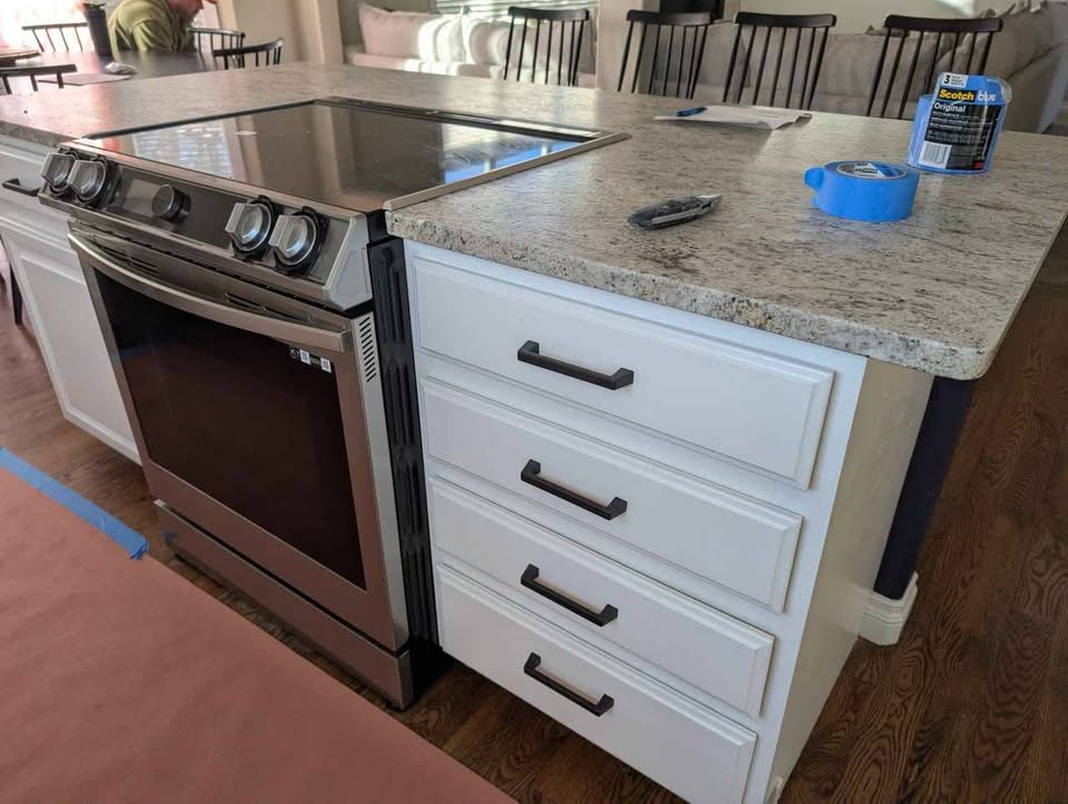White kitchen cabinets with stove, microwave, dishwasher and countertops.