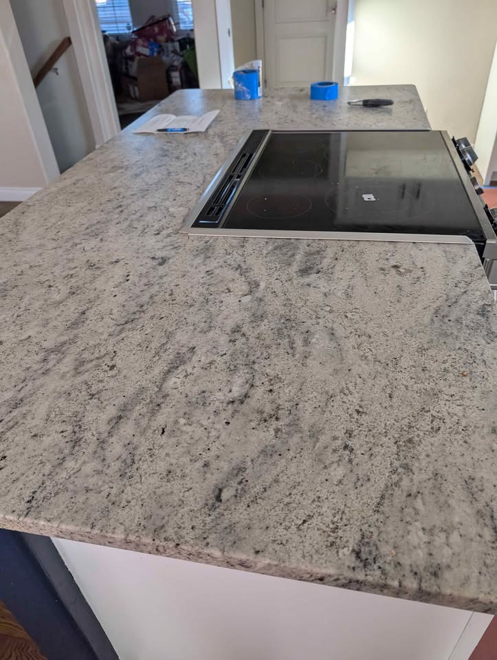 White kitchen cabinets with stove, microwave, dishwasher and countertops.