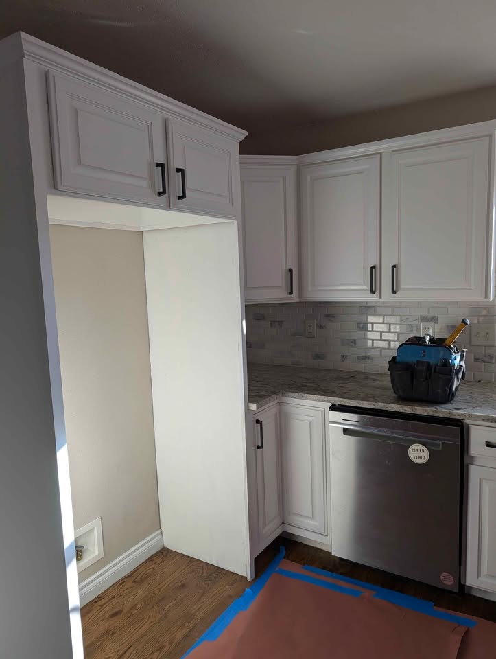 White kitchen cabinets with stove, microwave, dishwasher and countertops.