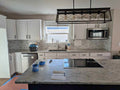 White kitchen cabinets with stove, microwave, dishwasher and countertops.