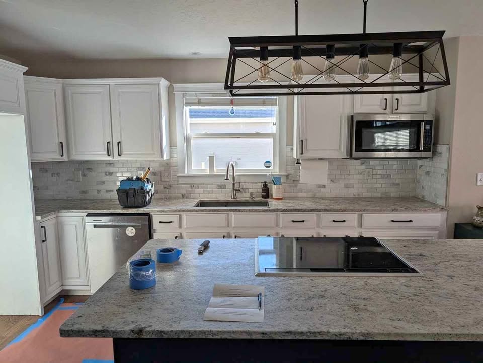 White kitchen cabinets with stove, microwave, dishwasher and countertops.