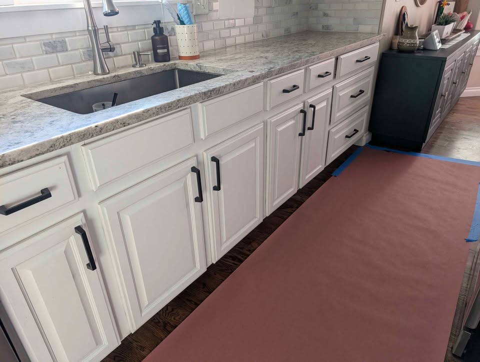White kitchen cabinets with stove, microwave, dishwasher and countertops.